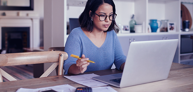 Mulher com descendência asiática utilizando uma camisa azul e pesquisando em um computador como tirar sua ideia de empreendimento do papel
