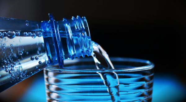 Garrafa enchendo copo de água para representar o processo de como montar uma distribuidora de água